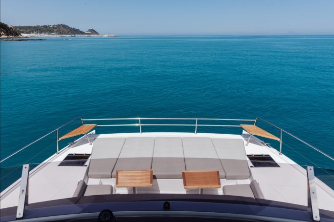 Prua di un yacht moderno con lettini su un mare turchese e cielo sereno.