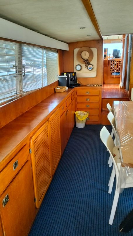 Interno di una barca, con armadietti in legno e tavolo da pranzo.