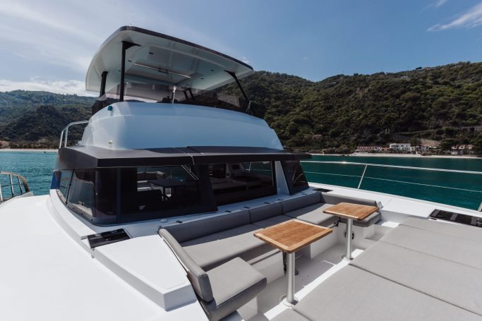 Cockpit of a modern yacht with sleek design and two small tables. Scenic waterfront backdrop.