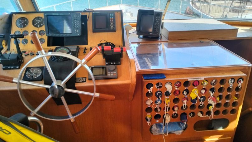 Pannello di controllo di una barca con timone, strumenti e comandi.