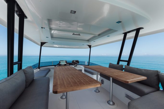 Spacious outdoor seating area on a boat with ocean views and wooden tables.