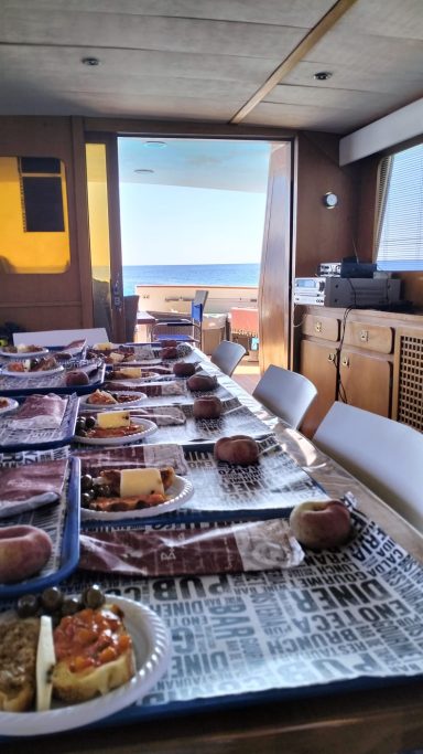 Table set with food in a cabin, with an ocean view through a large window.